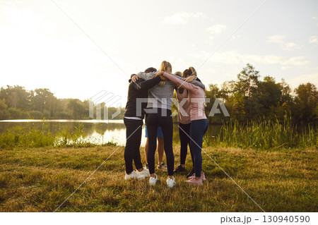 Group of people in sportswear standing in a circle hugging each other after sport workout. 130940590