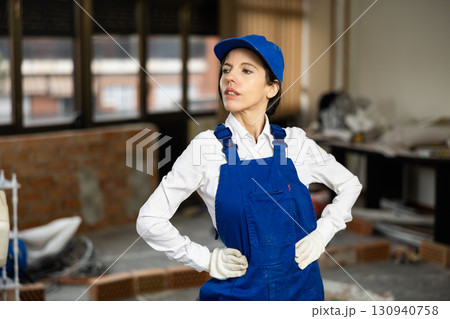 Woman construction worker posing inside house under renovation Woman construction worker posing inside house under renovation 130940758