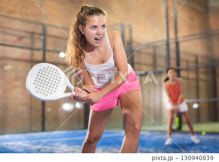 Emotional young sportswoman playing padel tennis on indoor court 130940839