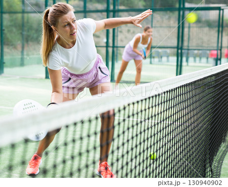 Woman playing padel tennis match during training on court Woman playing padel tennis match during training on court 130940902