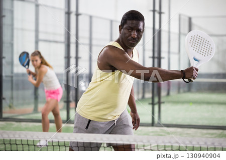 African American hitting backhand during paddle match in close court African American hitting backhand during paddle match in close court 130940904