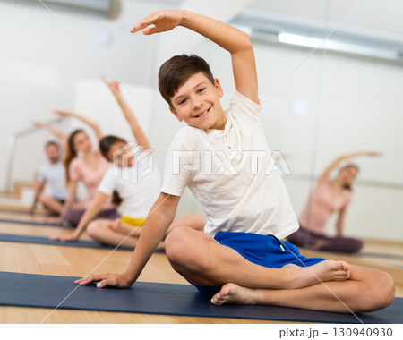 Tween boy doing stretching in lotus position during training with family 130940930