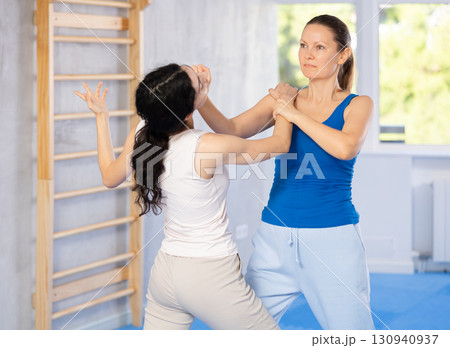 Active woman with professional female trainer are training captures on self-defense course in gym 130940937
