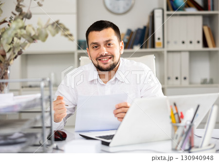 Smiling businessman doing his daily work in office Smiling businessman doing his daily work in office 130940948