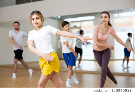 Girl dancing modern dance with family in gym 130940951