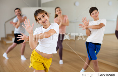 Girl dancing modern dance with family in gym Girl dancing modern dance with family in gym 130940966