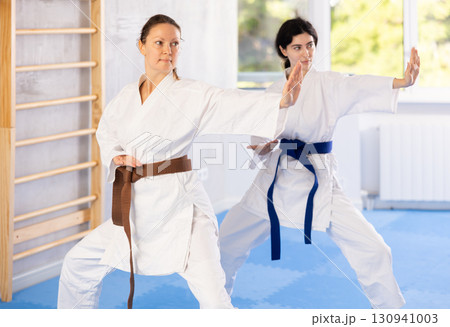 Women in kimono trying martial moves at karate class 130941003