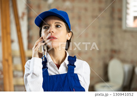 Woman builder using smartphone while standing in renovated room Woman builder using smartphone while standing in renovated room 130941052