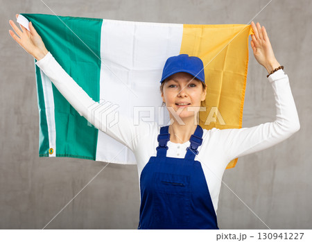 Smiling adult woman in uniform holding Ireland flag Smiling adult woman in uniform holding Ireland flag 130941227