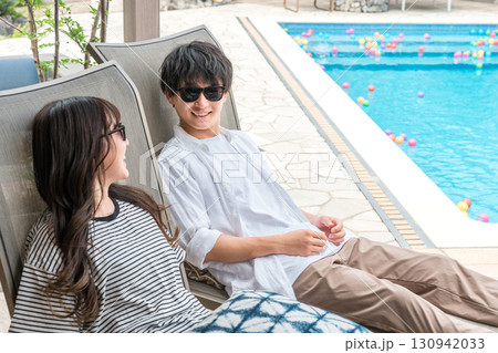 旅行でリゾートホテルのプールサイドに座るカップル,夫婦 旅行でリゾートホテルのプールサイドに座るカップル,夫婦 130942033