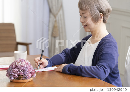 ご祝儀袋に筆ペンで表書きをするシニア女性 130942940