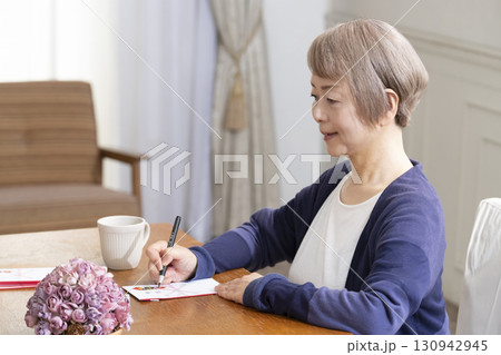 ご祝儀袋に筆ペンで表書きをするシニア女性 130942945