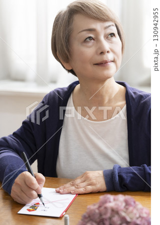 ご祝儀袋に筆ペンで表書きをするシニア女性 130942955