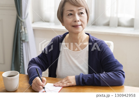 ご祝儀袋に筆ペンで表書きをするシニア女性 130942958