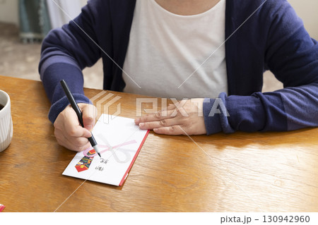 ご祝儀袋に筆ペンで表書きをするシニア女性 ご祝儀袋に筆ペンで表書きをするシニア女性 130942960