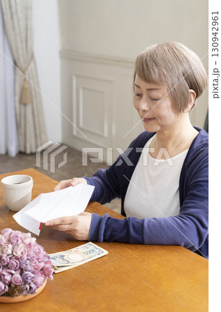 ご祝儀袋に筆ペンで表書きをするシニア女性 130942961