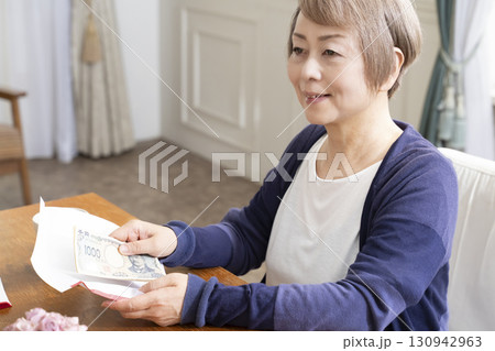ご祝儀袋に筆ペンで表書きをするシニア女性 130942963
