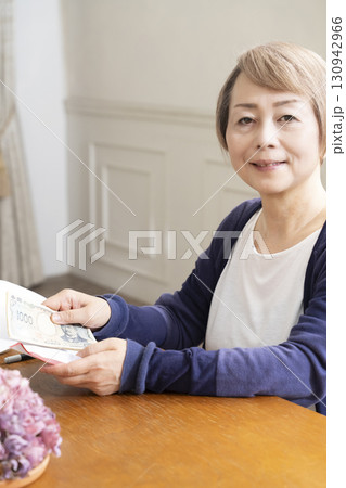 ご祝儀袋に筆ペンで表書きをするシニア女性 130942966