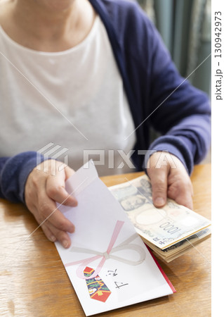 ご祝儀袋に筆ペンで表書きをするシニア女性 ご祝儀袋に筆ペンで表書きをするシニア女性 130942973