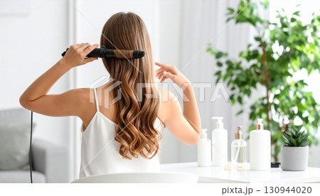 ヘアアイロンで髪の毛をセットしている女性の後ろ姿 ヘアアイロンで髪の毛をセットしている女性の後ろ姿 130944020