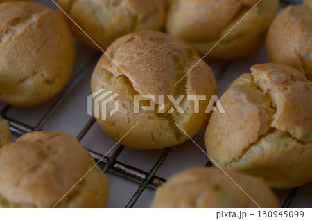Golden pastry puffs resting on a cooling rack after baking in a cozy kitchen 130945099