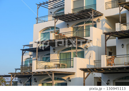 Charming coastal architecture with sunlit balconies inviting relaxation at a seaside retreat 130945113