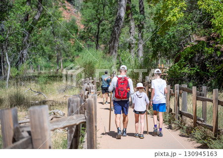 Family enjoys hiking together on a sunny day in a beautiful natural park setting Family enjoys hiking together on a sunny day in a beautiful natural park setting 130945163