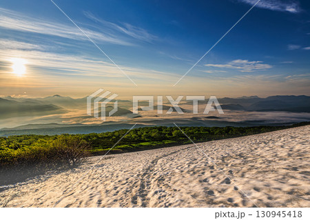 夏山登山道に残る雪と雲海に包まれた山並み 130945418