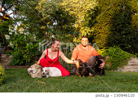 Happy couple enjoying garden time with four dogs at sunset 130946110