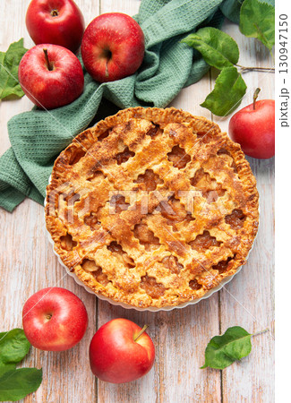 Freshly baked apple pie surrounded by ripe red apples and green leaves 130947150