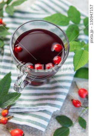 Rosehip tea brewing in glass cup with fresh rose hips and leaves 130947157