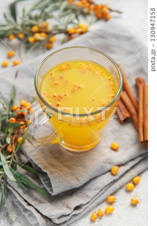 Sea buckthorn tea with berries and cinnamon sticks on grey napkins Sea buckthorn tea with berries and cinnamon sticks on grey napkins 130947158