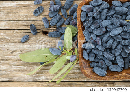 Fresh Blue Honeysuckle Berries in a Wooden Bowl on Rustic Wooden Background 130947709