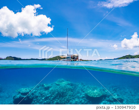 カタマランヨットのダイビングクルーズ船の半水面撮影。美しいサンゴ礁と熱帯魚の群れ。 沖縄県島尻郡慶良 130947910