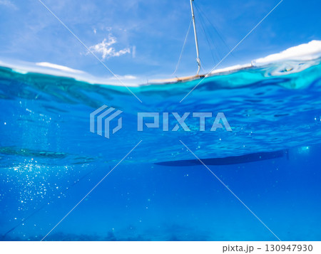 カタマランヨットのダイビングクルーズ船の半水面撮影。美しいサンゴ礁と熱帯魚の群れ。 沖縄県島尻郡慶良 130947930