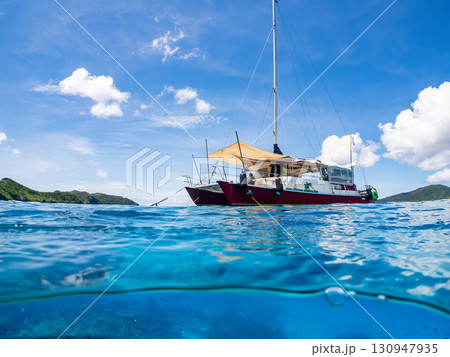 カタマランヨットのダイビングクルーズ船の半水面撮影。美しいサンゴ礁と熱帯魚の群れ。 沖縄県島尻郡慶良 130947935