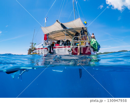 カタマランヨットのダイビングクルーズ船の半水面撮影。美しいサンゴ礁と熱帯魚の群れ。 沖縄県島尻郡慶良 130947938