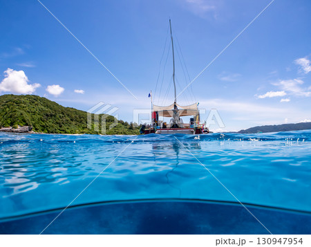 カタマランヨットのダイビングクルーズ船の半水面撮影。美しいサンゴ礁と熱帯魚の群れ。 沖縄県島尻郡慶良 130947954