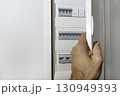 Male hand opening modern electrical panel with circuit breakers inside 130949393