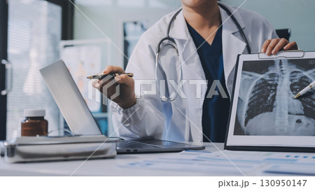 Medical team meeting analyzing blood test results in hospital laboratory. Doctors and scientists in lab coats are having a discussion about blood test result, holding test tubes and taking notes. 130950147