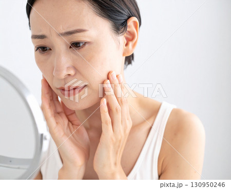 鏡を見て肌に悩む女性 130950246