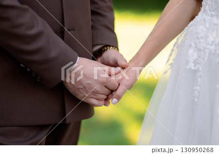 Couple holding hands during a wedding ceremony, embodying love and commitment while celebrating their unity and together future shared Couple holding hands during a wedding ceremony, embodying love and commitment while celebrating their unity and together future shared 130950268