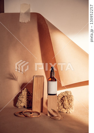 Modern still life blank mockup with bottle of serum on pedestals with natural materials on background of craft paper. Empty podiums for cosmetic organic product and others Modern still life blank mockup with bottle of serum on pedestals with natural materials on background of craft paper. Empty podiums for cosmetic organic product and others 130952257