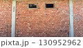 Rustic red brick wall with small windows in unfinished building 130952962