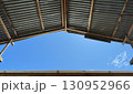 Rustic corrugated metal roof with wooden beams and blue sky 130952966