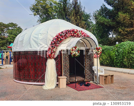 Asian wedding yurt, festively decorated with flowers and handmade carpets. 130953159