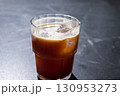 Refreshing iced coffee americano in a clear glass with ice cubes, placed on a dark surface, showcasing the rich color and texture of the beverage, perfect for summer enjoyment 130953273
