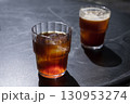 Two glasses of coffee iced americano and cold brew with ice cubes on a dark surface, showcasing rich colors and textures, perfect for summer refreshment and beverage enjoyment 130953274