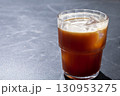 Refreshing iced coffee americano in a clear glass with ice cubes, placed on a dark surface, showcasing the rich color and texture of the beverage, perfect for summer enjoyment 130953275