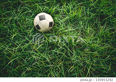 Soccer ball on lush green grass, showcasing the texture of the turf and the worn surface of the ball, evoking a sense of playfulness and outdoor activity, with copy space Soccer ball on lush green grass, showcasing the texture of the turf and the worn surface of the ball, evoking a sense of playfulness and outdoor activity, with copy space 130953292
